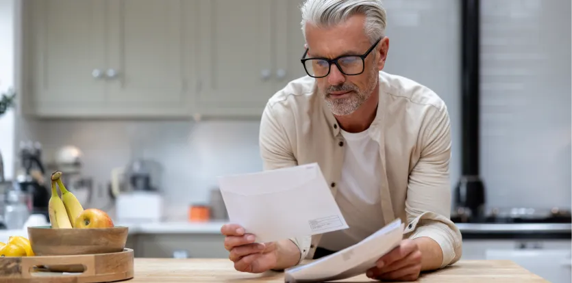 Hombre mayor leyendo documentos en la cocina