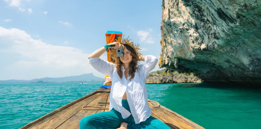 Mujer sonriendo mientras toma una foto en un bote frente al mar